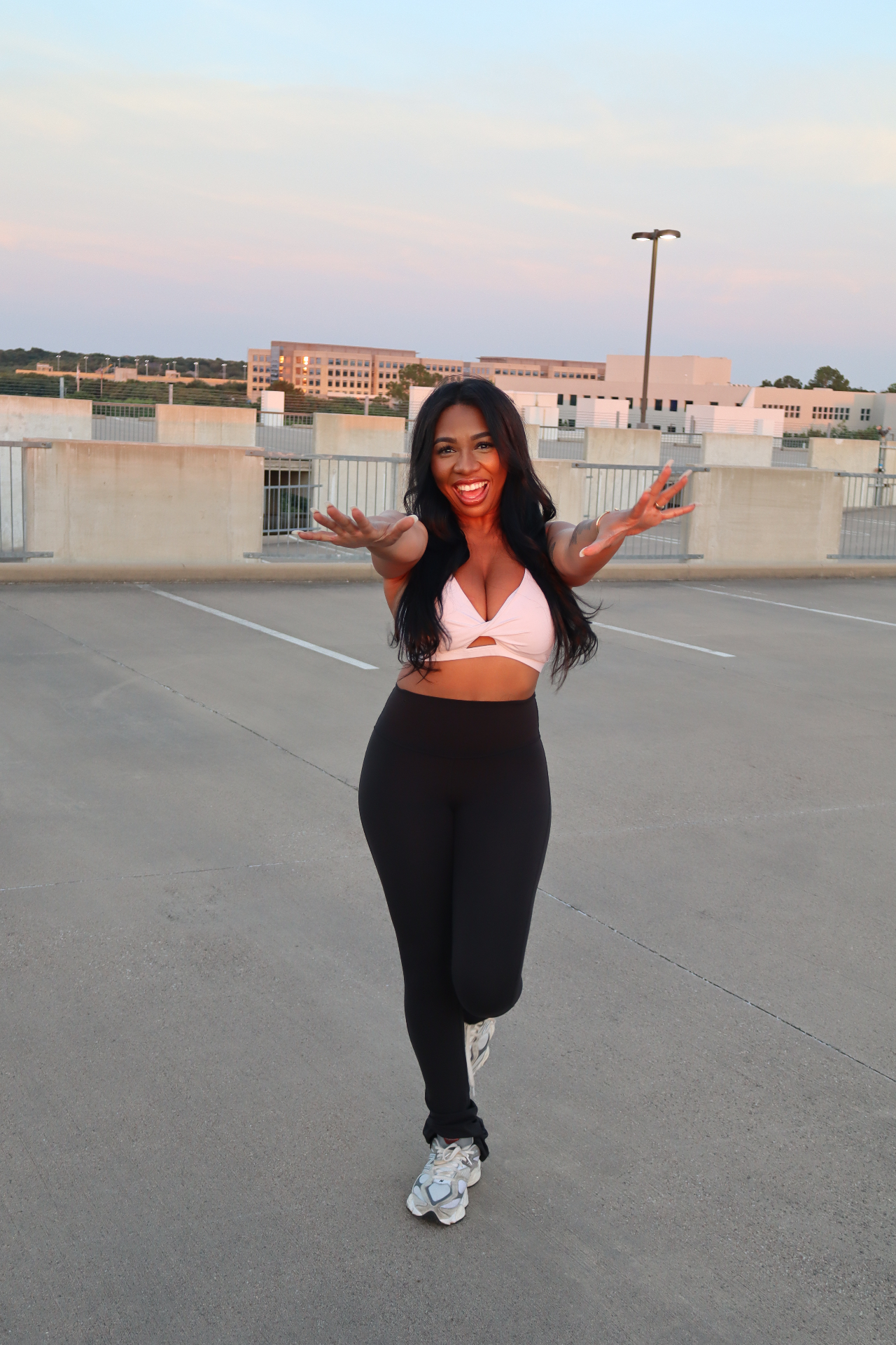 Bree with arms open, smiling on a rooftop