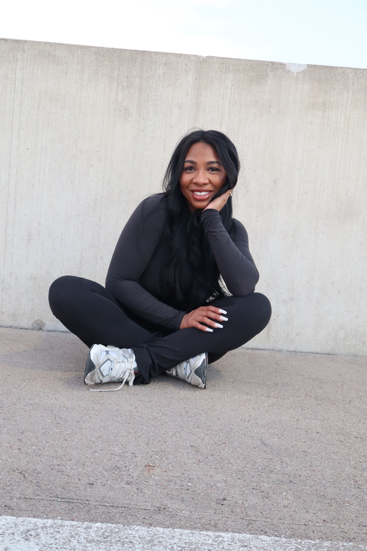 Bree, founder of Resolvebody, seated against a concrete wall